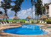 Refreshing outdoor pool with poolside chairs and bamboo huts.