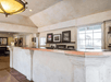 The light colored stone front desk for the Baechtel Creek Inn with a window and several pictures on the wall behind it.