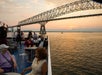 Guests sitting outside on the deck enjoying drinks and charring at sunset on the Signature Spirit of Baltimore Dinner Cruise.