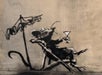 A spray-painted stencil of a lounging rat holding a martini glass, reclining on a deck chair next to a clothesline, on a weathered wall.