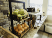 An breakfast buffet area with an assortment of fresh fruits on a tiered display, hot sauces, and silver warming containers.