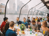 A dining room full of people enjoying their meal next to a glass wall showing the city on the Bateaux New York Premier Brunch Cruise