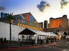BattleBots arena with a large tent and signage, surrounded by temporary fencing. City skyline in the background at sunset.