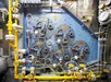 Industrial valve control panel with multiple levers, gauges, and pipes, featuring prominent yellow and blue components.