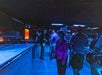 People with cameras walk through a dimly lit room filled with equipment and monitors.
