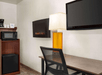 Desk, flat-screen TV, mini-fridge, microwave, and a coffee machine inside a guest room.