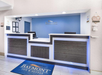 Hotel reception desk with two computer monitors, a blue and white color scheme, and a Baymont Inn & Suites logo on the wall and floor mat.