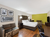 One king bed, bedside lamps, TV, desk,  and a seating area in a guest room.
