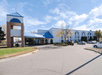 The white and blue exterior of the Baymont by Wyndham Shakopee on a sunny day with cars in the parking lot.