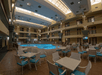 The large atrium with a swimming pool, hot tub, and several sets of tables and chairs at the Baymont by Wyndham Shakopee.