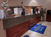 The dark brown and gray front desk with flowers sitting on it at the Baymont by Wyndham Shakopee with a bright blue rug in front of it.