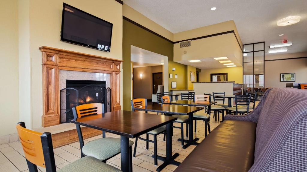 Hotel lobby with a cozy fireplace, wall-mounted TV, and arranged seating including tables and chairs.