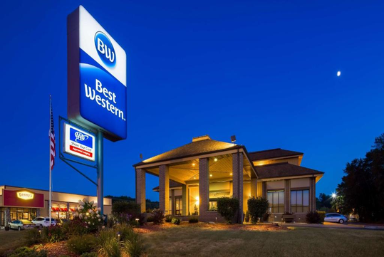Exterior view of a Best Western hotel at dusk, featuring a large sign and a well-lit entrance with surrounding landscaping.