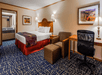 One king bed, seating area, and work desk and chair inside a guest room.