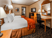 Two double beds, working area, and a flat-screen TV inside a guest room.