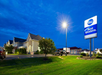 Best Western hotel exterior at dusk, with illuminated sign and parking lot in the foreground, under a cloudy sky.