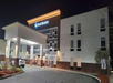 A Best Western hotel building at night with exterior lights on and a parked car near the entrance.