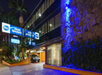 Night view of a Best Western hotel exterior with blue lighting, reflective glass windows, and a parked SUV at the entrance. Signs for "2011" and "Spice" are visible.