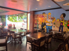 An empty restaurant interior with wooden tables and chairs, featuring a colorful wall mural of animated characters dining.