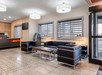 Hotel lobby with modern black leather chairs, sofa, coffee table, and an ATM. Contemporary decor includes patterned floor tiles, wall art, and two large ceiling lights.