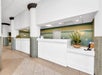A modern reception area with white counters, green walls, and decorative plants.