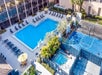 Aerial view of a hotel pool area with a large swimming pool, loungers, a small jacuzzi, and a nearby basketball court.