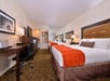 Two queen beds, a flat-screen TV, and a work desk inside a guest room.