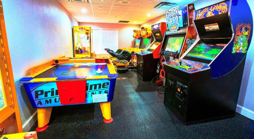 A small arcade room with an air hockey table and several upright arcade game machines lined against the walls under ceiling lights.