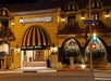 Exterior view of the Best Western Plus Sunset Plaza Hotel at night, featuring a striped awning and illuminated signs, located on Sunset Boulevard.