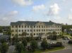 Aerial view looking at the front exterior of the Best Western Plus Valdosta Hotel & Suites with a blue cloudy sky overhead.