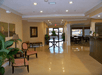 The lobby of the Best Western Plus Valdosta Hotel & Suites with a large brown front dest, several chairs and seating options, and a dining room in the background.