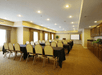 A meeting room with long black cloth covered tables with white chairs lined up in front of a podium and a projector screen at the Best Western Plus Valdosta.