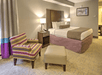 A cozy guest room featuring a king bed and a comfortable armchair with ottoman.