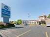 Exterior view of Best Western Summit Inn, with a parking lot, some cars, and flags fluttering near the entrance under a clear blue sky.