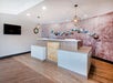 Modern hotel reception area with two counters, pendant lights, and a decorative wall featuring abstract art in soft colors.