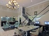 A hotel lobby with a staircase, chandelier, seating area, and computers on a table.
