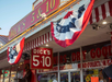 Exterior of Dick's 5 & 10 store with red, white, and blue bunting. The shop has large windows displaying various items and a red and white striped awning.