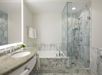 A modern bathroom with marble tiles, featuring a glass-enclosed shower, a bathtub, a granite countertop with a sink, and a mirror. Towels hang on the wall, and toiletries are visible.