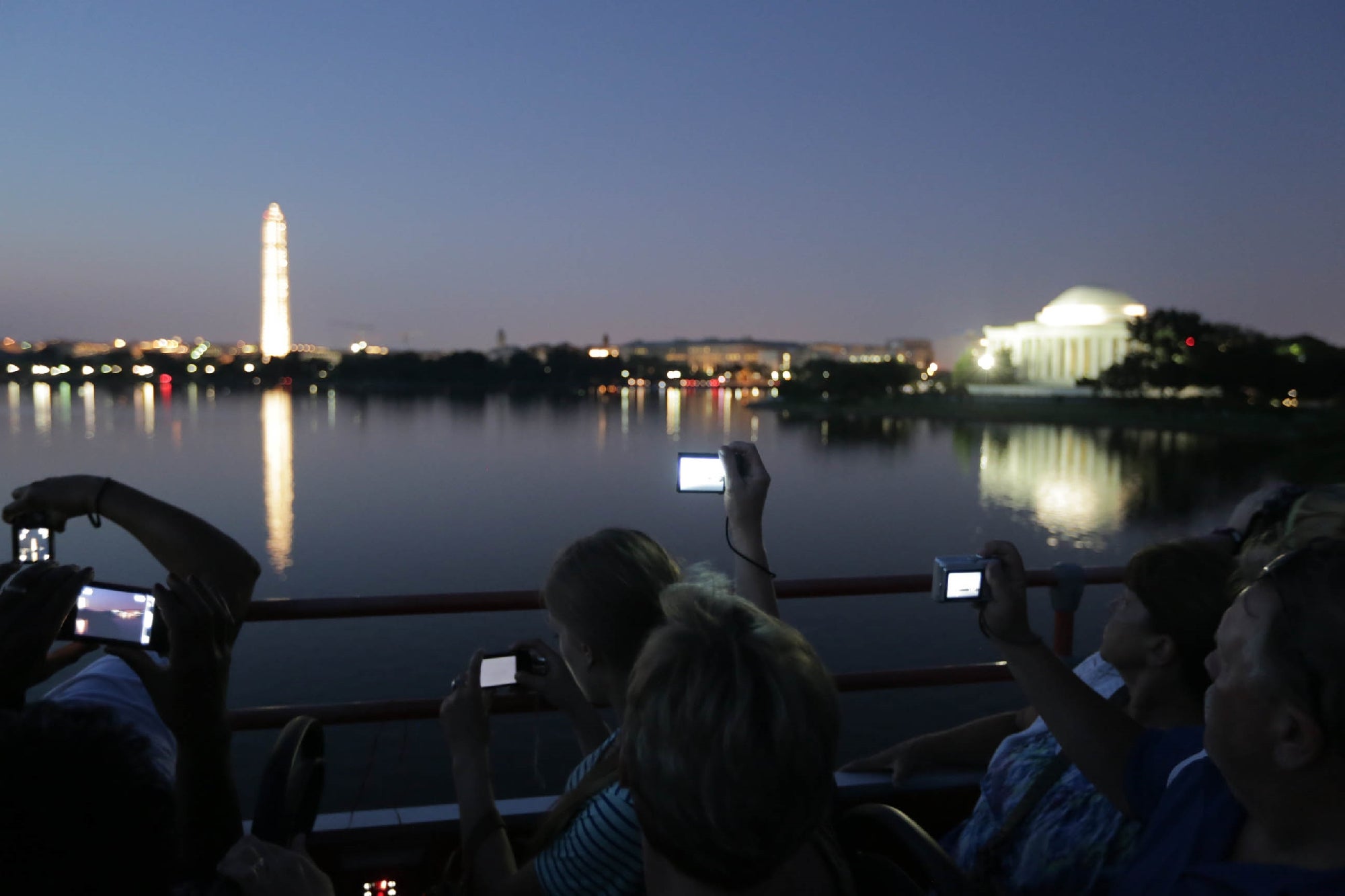 People taking photos at dusk of the Washington Monument and Jefferson Memorial across the water.