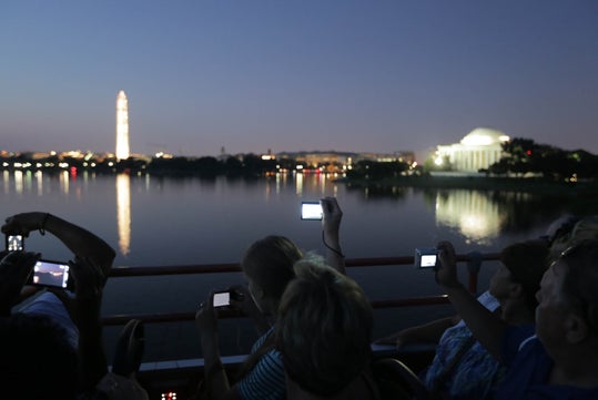 People taking photos at dusk of the Washington Monument and Jefferson Memorial across the water.