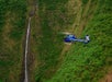 A helicopter flying by a cliffside with a small waterfall flowing over the edge on Big Island's Kohala Coast Adventure Helicopter Tour in Hawaii USA.