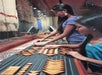 Two young women interact with a hands-on exhibit, arranging geometric wooden shapes on a display board in a museum setting.