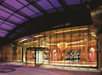 Glass entrance to a modern building with purple-tinted ceiling and illuminated interior showcasing colorful art installations.