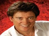 Close up photo of Ronnie McDowell smiling with a red background.