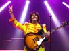 A man in a yellow costume playing the guitar in the British Invasion Show at the Americana Theatre in Branson Missouri.