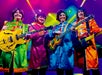 A group in colorful clothes performing in the British Invasion Show at the Americana Theatre in Branson Missouri.