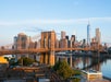 A view of the Brooklyn Bridge spanning the East River with the New York City skyline in the background during daytime.