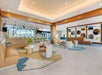 Modern hotel lobby with beige furniture, geometric rugs, and a backlit bar area. Circular wall art enhances the contemporary design.