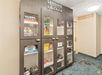 Lending locker cabinet with games, small appliances, and board games in a hallway next to a gym and laundry sign.