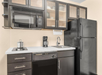 Compact modern kitchen with black appliances, including a refrigerator, oven, microwave, and dishwasher. There is a small sink, electric cooktop, and coffee maker on the countertop.